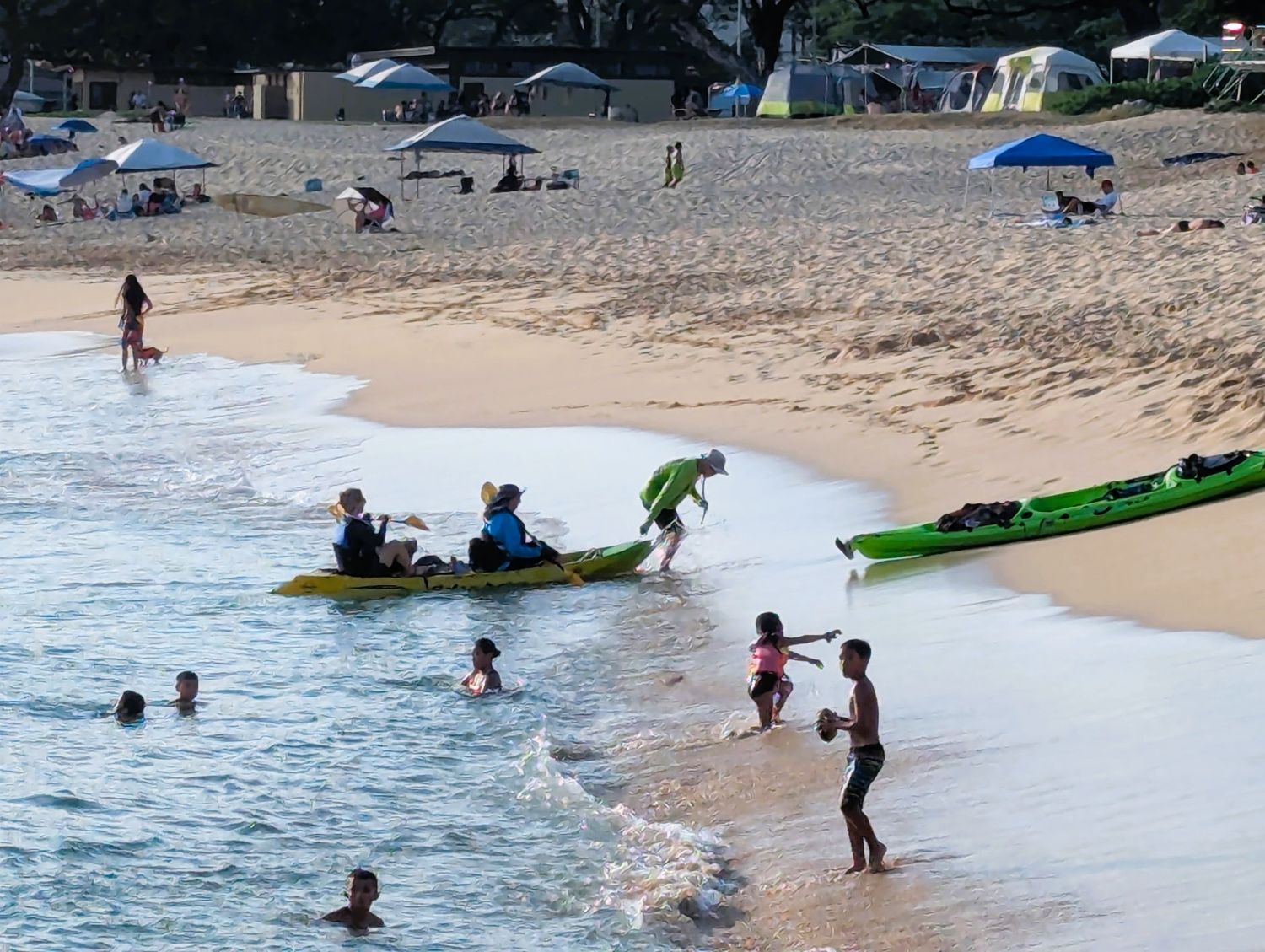 Man assists a tandem kayak landing on the beach