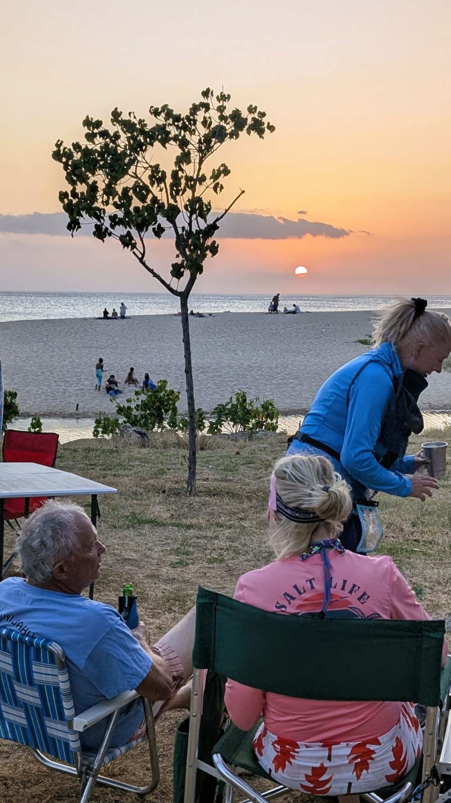 Man and a woman sitting at the beach watching the sunset