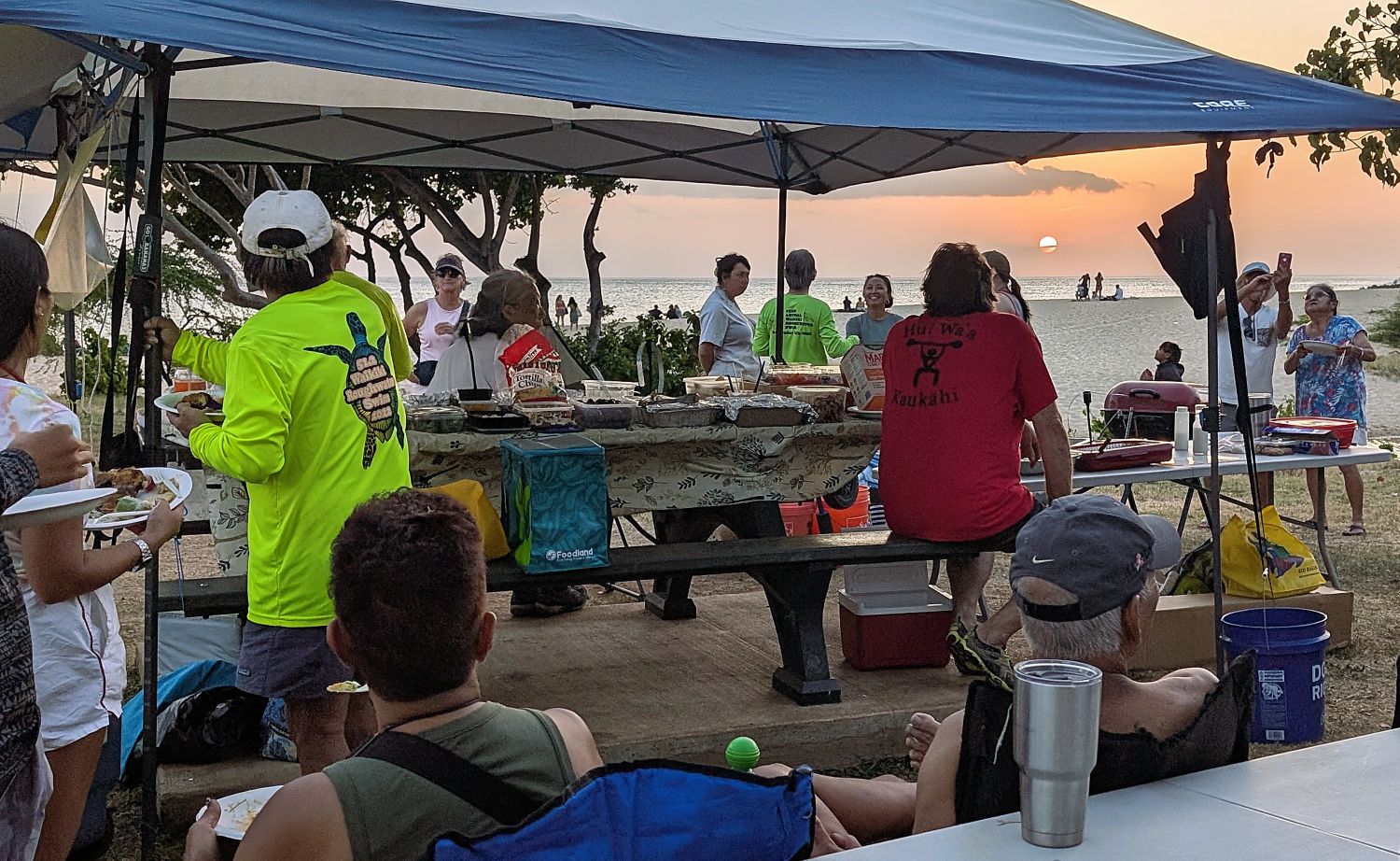 Sunset visible through a canopy covering a potluck picnic spread
