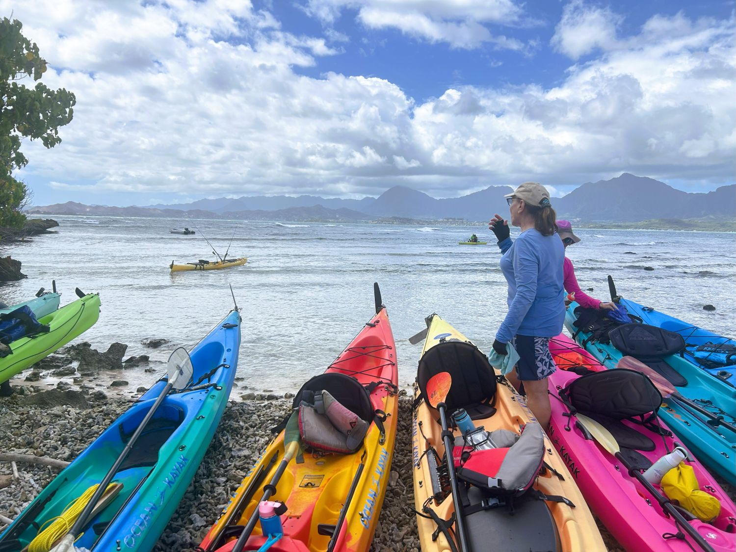 Woman looking at the water while standing among beached kayaks