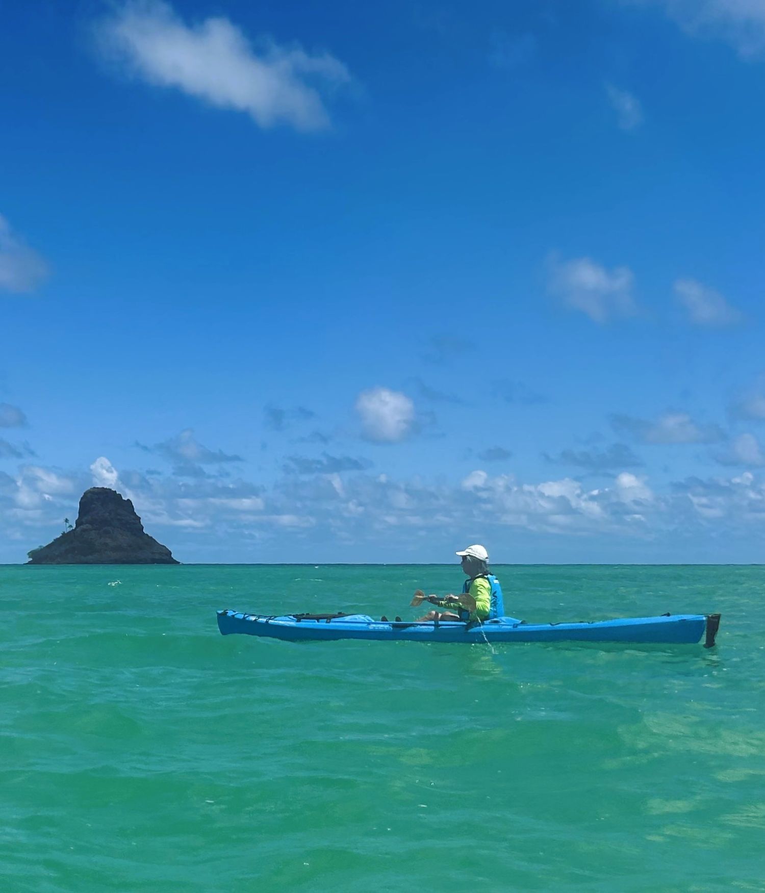 Kayaker on calm green water with Mokoli'i in the background