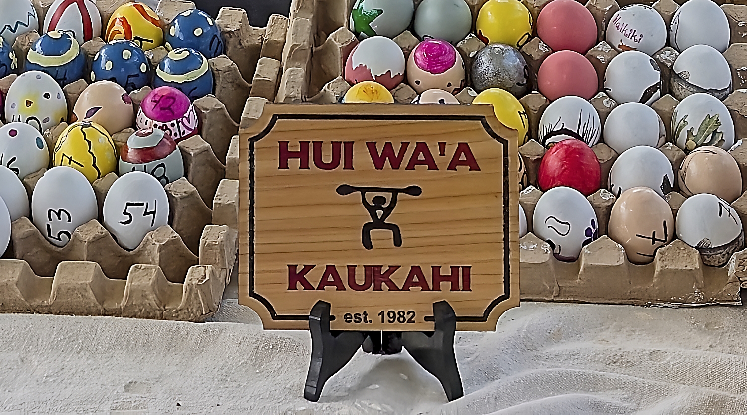Hui Wa'a Kaukahi plaque in front of tray of painted wooden Easter eggs