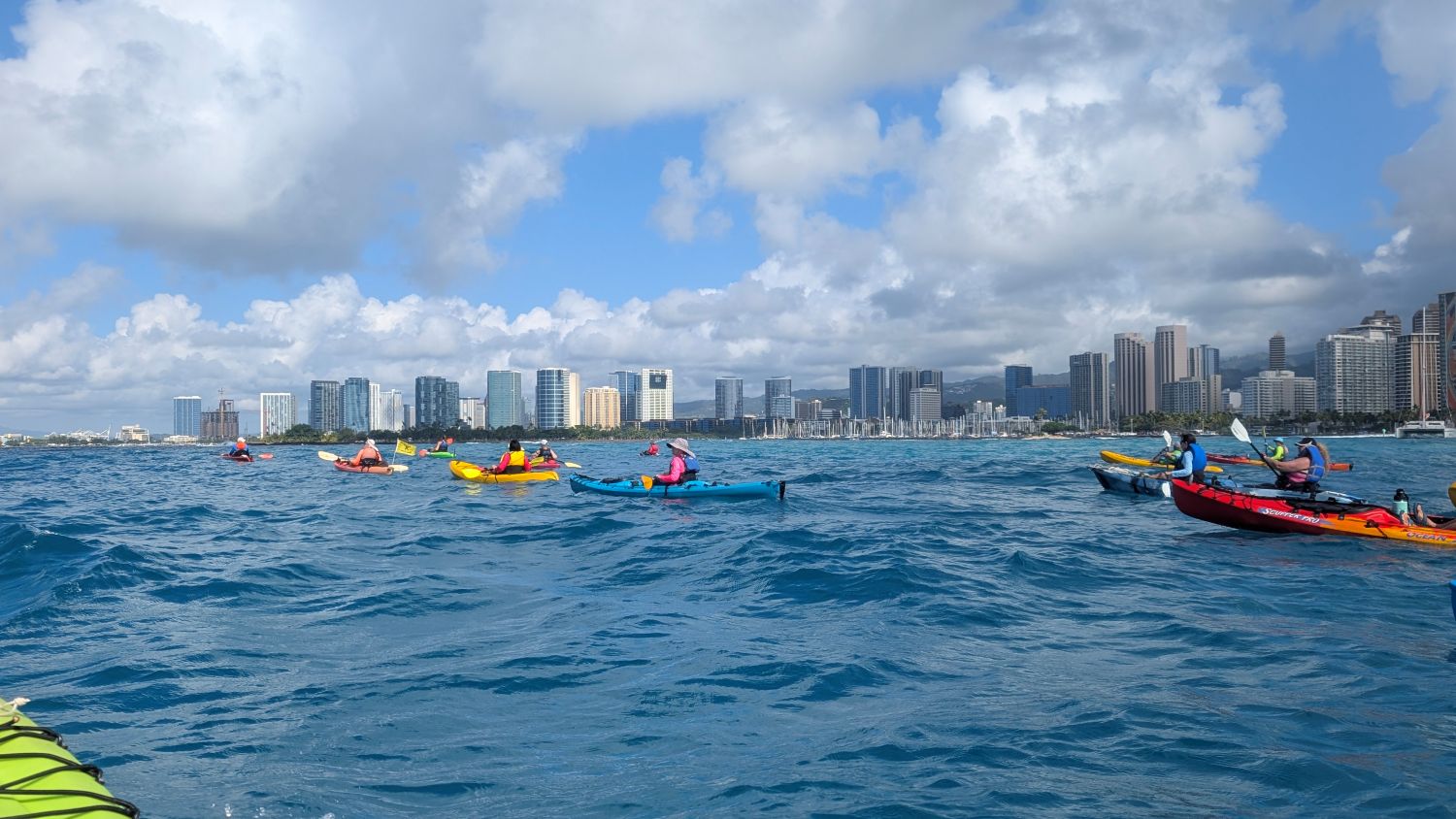 A line of kayakers on the ocean outside of Waikiki.