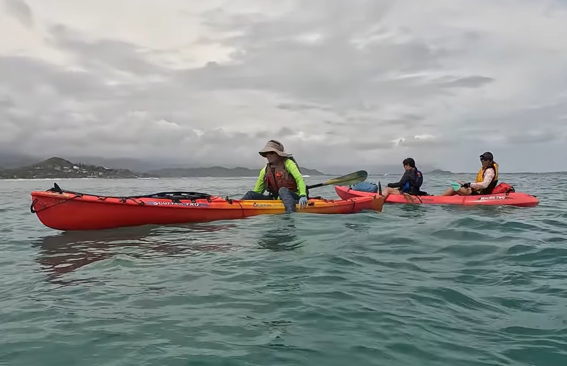 A single and tandem kayak on the water with Kailua Beach in the background