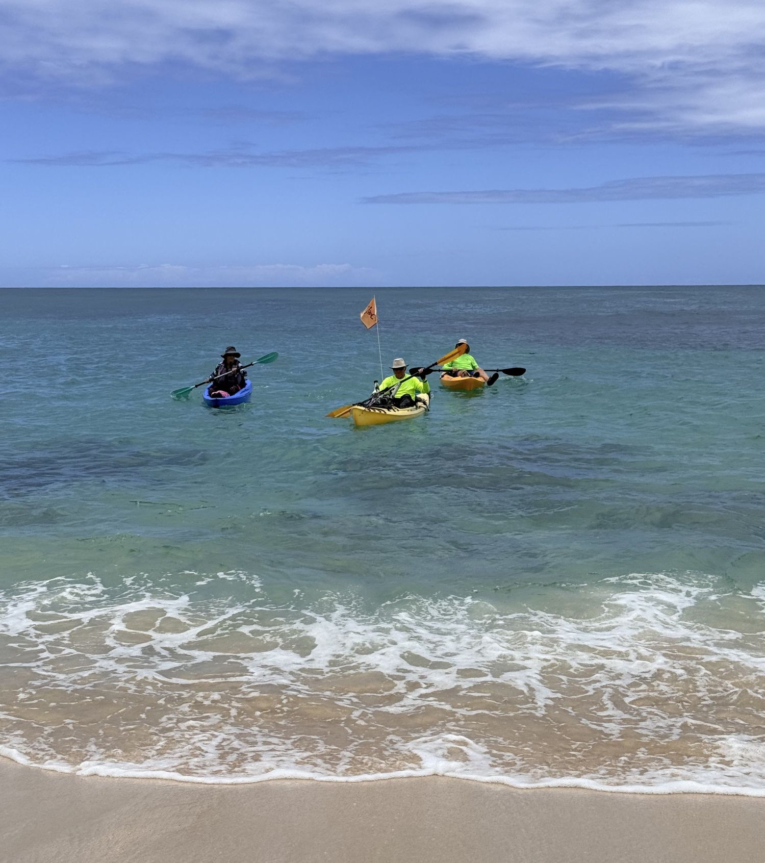 Three kayakers approaching the beach landing