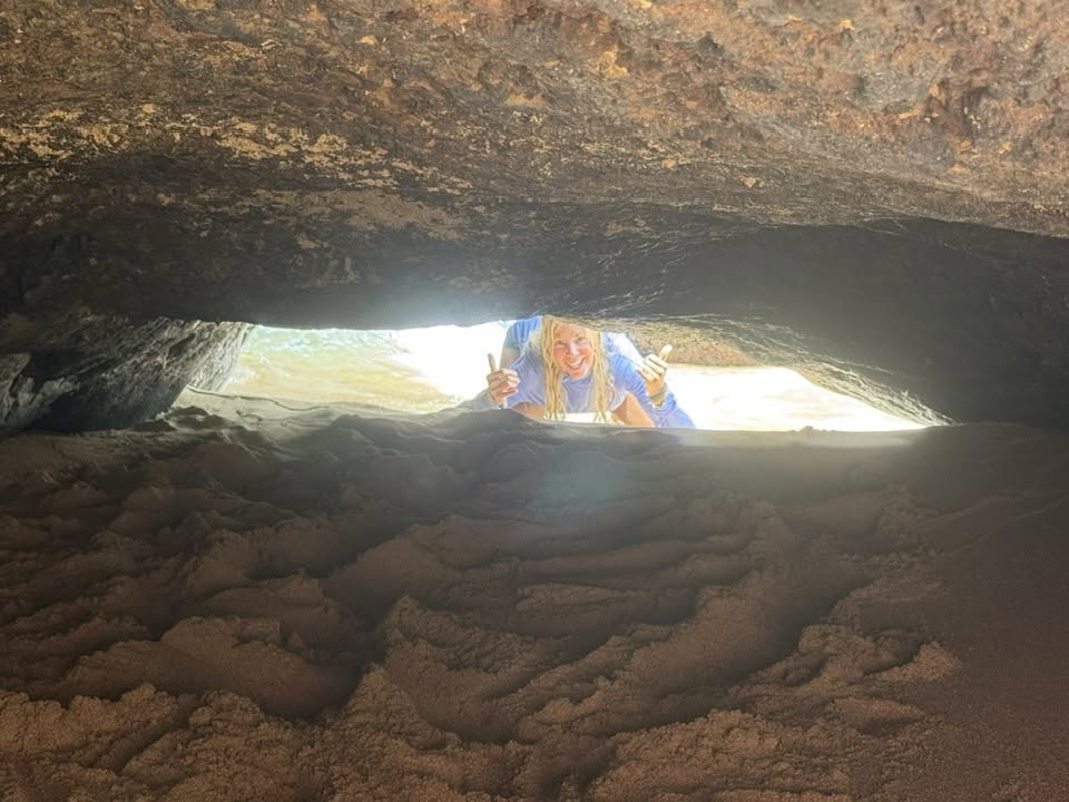 Woman looking into a sand filled cavern from the open end of the cavern